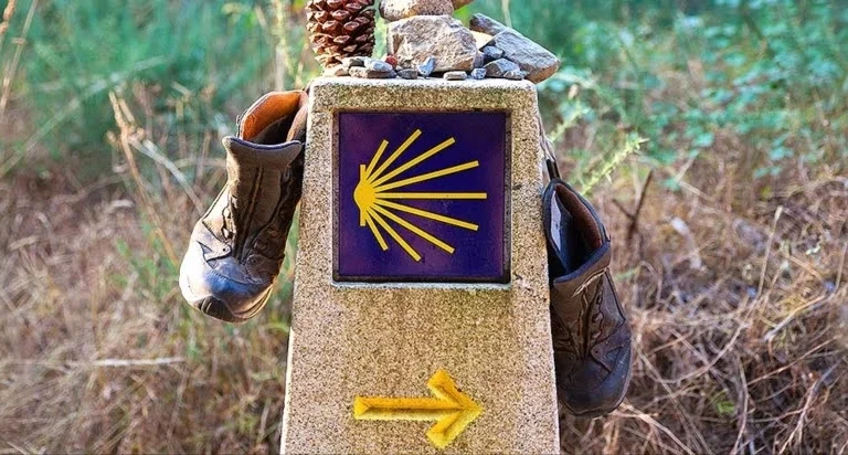 Betonowe oznaczenie Szlaku Świętego Jakuba, na którym są przewieszone buty.