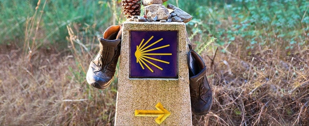 Betonowe oznaczenie Szlaku Świętego Jakuba, na którym są przewieszone buty.
